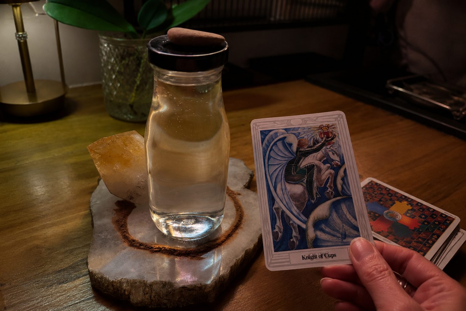 The Knight of Cups tarot card beside a glass of water and a citrine crystal